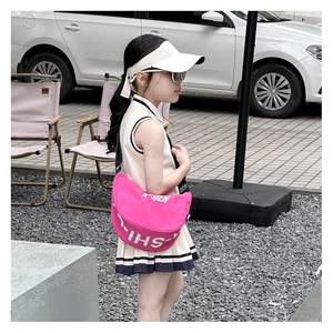 Close-up of a pink crossbody half-moon bag with ASJEN letters on a girl in white dress