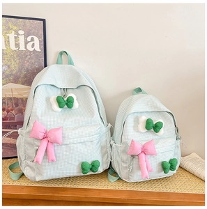 Detailed comparison of large and small green plaid backpacks with pink bows