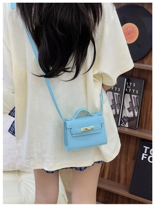 Detail of light blue mini crossbody bag with gold lock buckle and lychee leather texture
