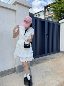 Détail de la robe sans manches en dentelle blanche avec nœud noir élégant et jupe à volants