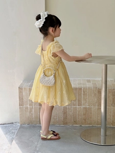 Detail of child wearing a pale yellow seersucker dress with white floral embroidery