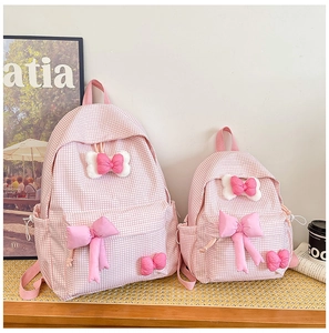 Pink plaid backpack with bow ties in large and small sizes for girls on wooden table