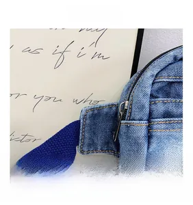 Détail du sac de poitrine en denim bleu avec surpiqûres jaunes et fermeture éclair en métal