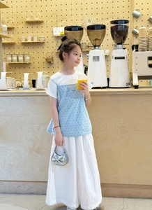 Close-up of a silver bow mini handbag styled with a blue polka dot vest and white dress