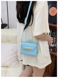 Detail of light blue mini crossbody bag with golden clasp and lychee texture