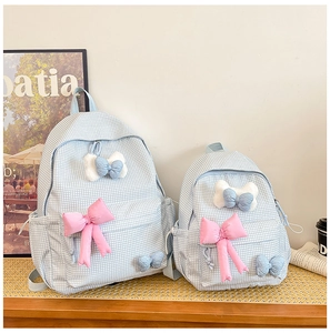Detail of light blue plaid backpack set with cute pink bows and canvas texture