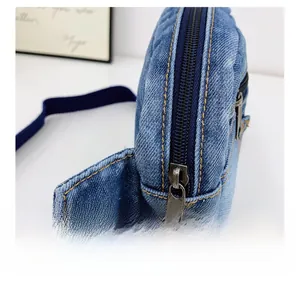 Détail de la fermeture éclair en métal bronze sur un sac de poitrine en denim bleu