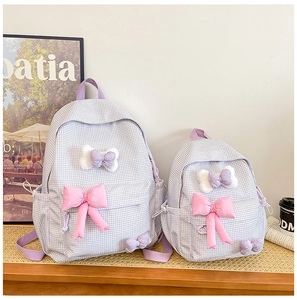 Detailed comparison of large and small plaid backpacks with decorative pink bows