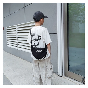 Detail of a black crescent crossbody bag with white X-SJEN lettering and adjustable strap