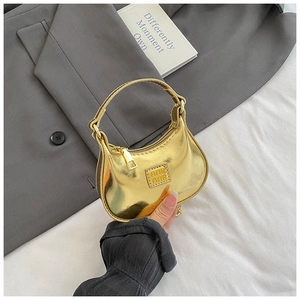 Gros plan d'un mini sac à main doré brillant avec poignée et détails de chaîne en métal