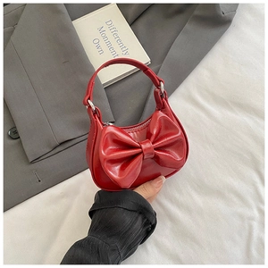 Detail of red mini handbag with oversized bow decor on a stylish fashion background