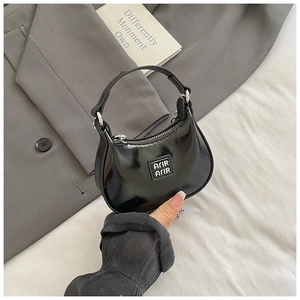 Détail d'un mini sac à main en cuir verni noir avec fermeture éclair argentée chic