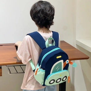 Sac à dos enfant motif excavatrice bleu et vert, porté par un enfant au bureau