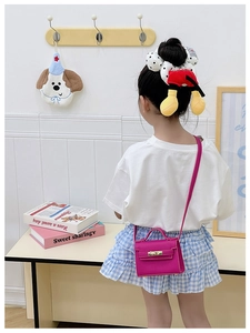 Detail of a mini fuchsia leather bag for kids with gold lock and detachable strap