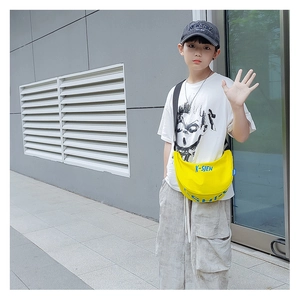 Detail of a bright yellow canvas dumpling bag worn by a young boy on a grey background