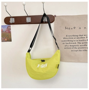 Close-up of neon yellow dumpling crossbody bag with adjustable black nylon strap