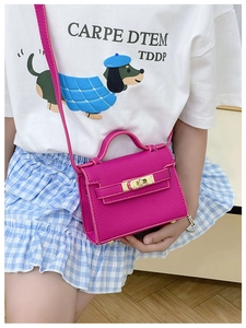Detailed macro view of rose red litchi grain leather bag with golden metal buckle