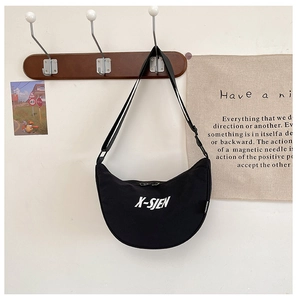 Detail view of black canvas crescent bag with white letter print and adjustable strap