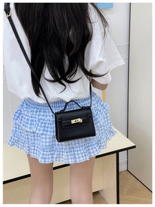 Detailed view of black litchi textured mini crossbody bag with golden twist lock closure