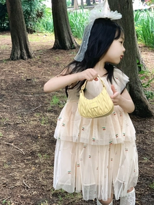 Detail of a beige mesh dress with cherry embroidery and a yellow quilted tote bag for girls