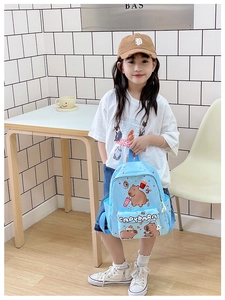 Detail view of cute light blue kid's backpack featuring cartoon capybara prints and zipper pocket