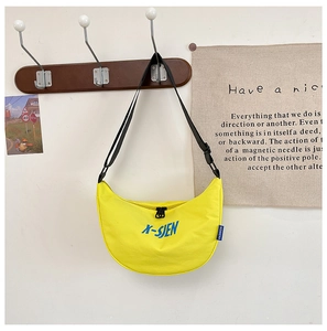 Detail of yellow canvas dumpling bag with blue lettering and adjustable strap