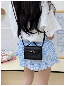Detail of black mini crossbody bag with gold buckle and lychee leather texture for kids