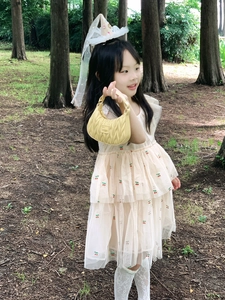 Close-up of yellow pleated mini handbag featuring elegant metallic logo for kids