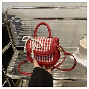 Detail der rot-weiß karierten Kindertasche mit Perlen-Schleifen-Anhänger und Lederbesatz
