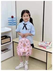 Pink Capybara print kids backpack shown on model in a cozy indoor setting
