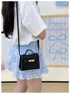 Detail of black mini crossbody bag with gold twist lock and lychee leather texture