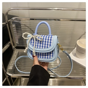Detailansicht der Mini-Karotasche mit Perlen-Bogen-Anhänger und blauem Leder