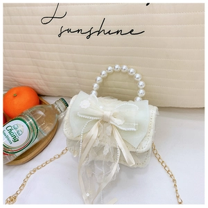 Detail der weißen Mini-Tasche mit Perlengriff und Netzschleife für Mädchen in Lifestyle-Szene