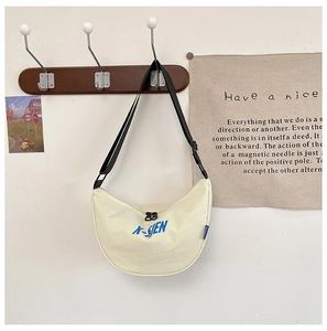 Close-up of canvas dumpling bag with blue letter print and adjustable black strap