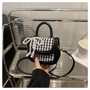 Detail der Mini-Mädchen-Handtasche mit Karomuster, Perlbogen und Lederriemen
