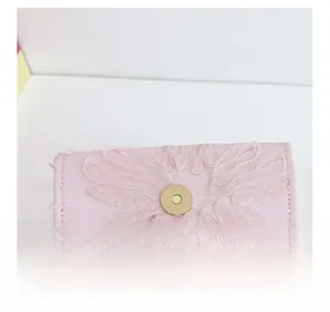 Détail du tissu en dentelle rose avec boucle magnétique dorée sur un sac pour enfant