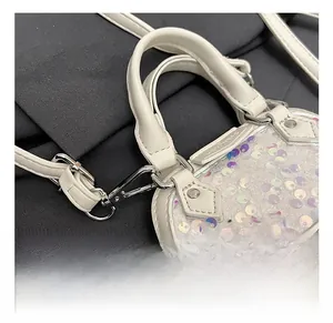Détail du crochet métallique argenté et paillettes sur le mini sac bandoulière blanc