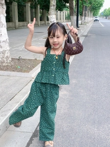 Detail of dark green polka dot sleeveless top with row buttons and ruffle hem