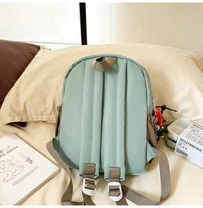 Detail view of the mint green backpack's back with adjustable brown shoulder straps