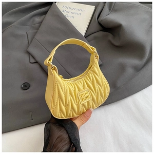 Detail of a bright yellow pleated mini handbag with embossed AMIR AMIR logo for girls