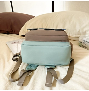 Detail view of large schoolbag showing mint green and brown fabric with side charm