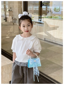 Petite fille avec un sac à main princesse en dentelle bleue et perles.