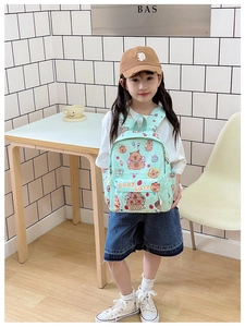Mint green school backpack with cute Capybara patterns worn by a young girl in a cafe