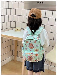 Detail of mint green plaid backpack featuring cute cartoon capybara prints and side pockets