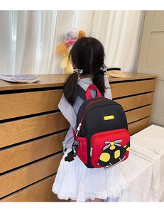 Kid back view of red and black backpack with cartoon helicopter and bag charm