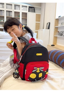 Close-up of red and black cartoon helicopter backpack for kids with a cute bear charm
