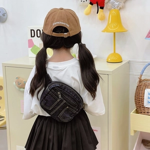 Sac de poitrine en denim noir pour enfants avec sangle réglable dans un décor cosy