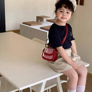 Rote karierte Kindertasche mit Perlenanhänger, getragen von Mädchen im Café-Stil
