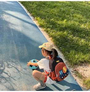 Close-up of child carrying cute blue cement mixer backpack with red shoulder straps