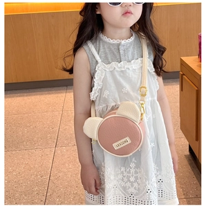 Close-up of pink bear-shaped crossbody bag worn by a girl in a white lace dress